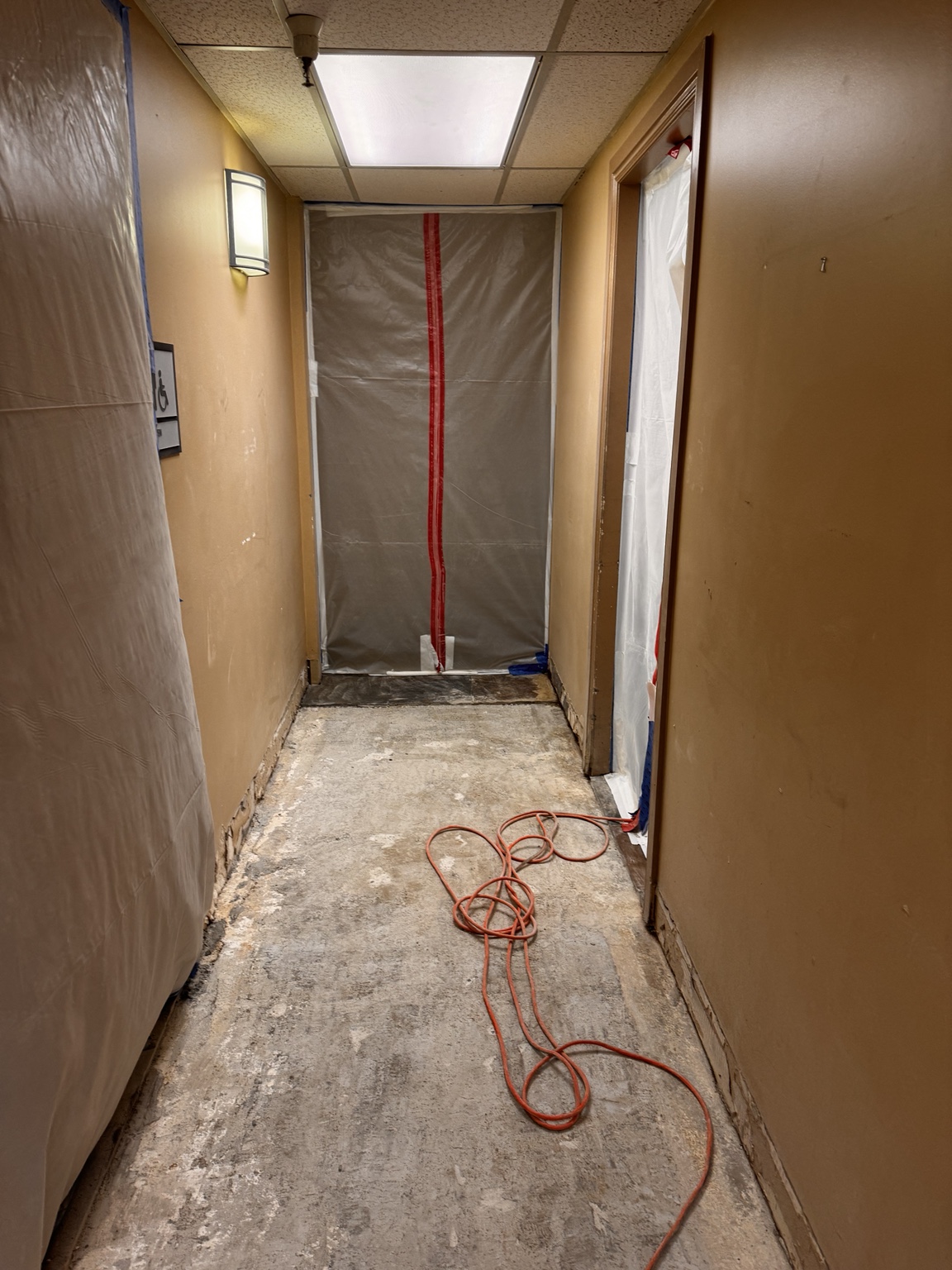 Airport hallway after floor tile removal, with doorway barriers in place